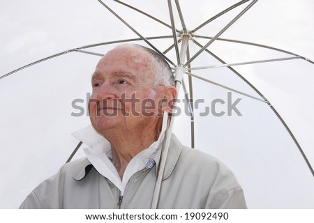 senior man sitting under an umbrella in the hot sun