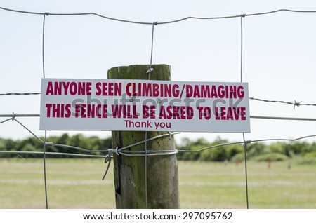 A sign saying climbing this fence may damage it, England UK.