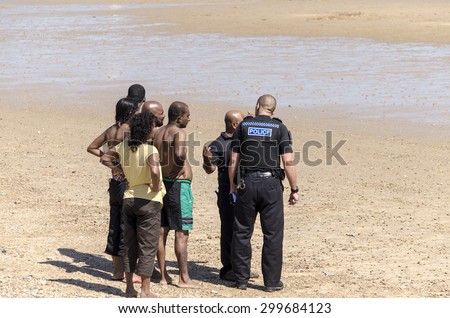 Clacton-on-sea, Essex, England UK: 1 August 2013- A group of colored men talking to a police man on the beach, when on a day out  to the seaside.