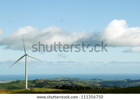 Giant wind turbine on hill. Coastline in background