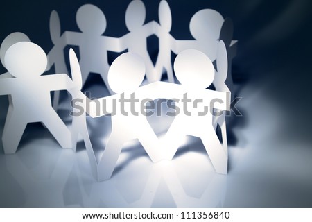 Team of paper doll people holding hands in a circle