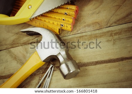 Hammer, nails, ruler and saw on wood