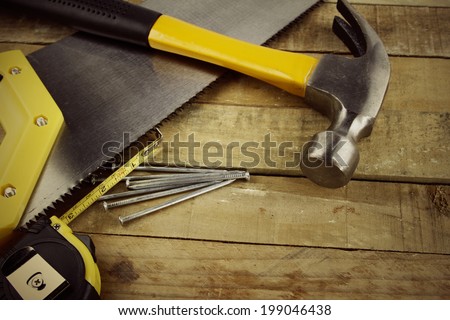 Hammer, nails, tape measure and saw on wood