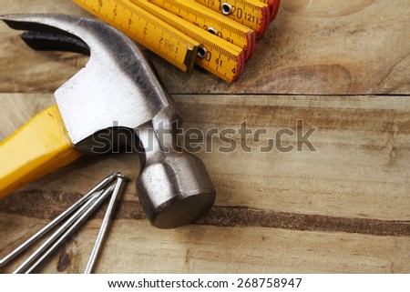 Hammer, nails and folding ruler on wood