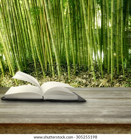 Open book on table in front of bamboo forest