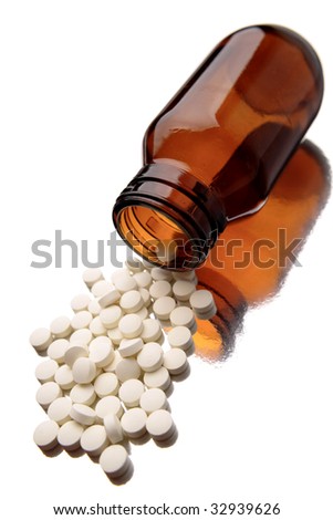 Pills spilling from bottle on white background