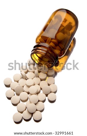 Pills spilling from bottle on white