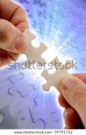 Fingers holding two puzzle pieces over bright background