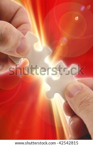 Fingers holding two puzzle pieces over bright background