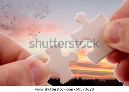 Fingers holding two puzzle pieces