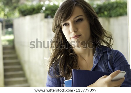 Portrait of a college student with book and mobile phone