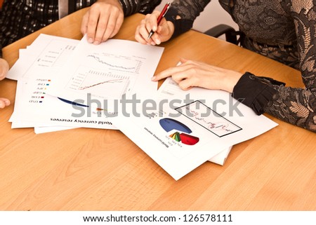 Papers On Desk With Diagrams And Hands Pointing At Growth.