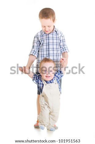 happy baby boy doing first steps with help of elder brother