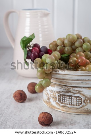 Grapes in white, vintage ceramic bowl, nuts and white ceramic jug