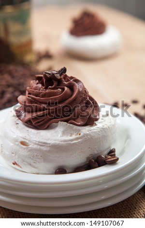 Meringue with coffee cream coffee beans spilled in the background, blurred, metallic coffee can, sackcloth, white desert plates