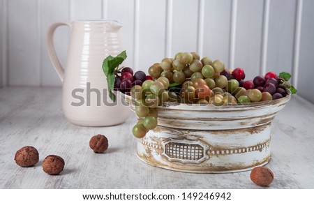 Grapes in white, vintage ceramic bowl, nuts and white ceramic jug