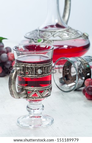 Red wine in vintage crystal and silver glassware, a crystal and silver decanter and red grapes besides.