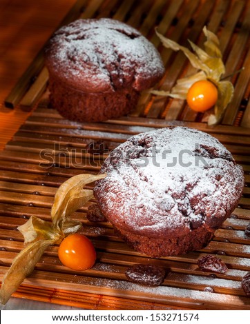Chocolate chip muffins on wooden cutting board, in a dark corner, with exotic fruit