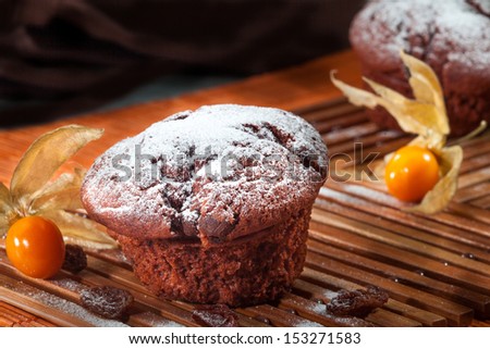 Chocolate chip muffins on wooden cutting board, in a dark corner, with exotic fruit