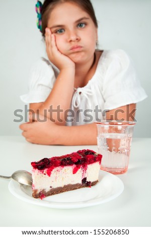 Little caucasian, european girl, brown hair, blue eyes, eating cheesecake, sad