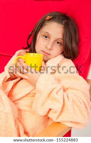 Little girl, caucasian, european, brown hair, blue eyes, dressed in a robe, sitting in an armchair with the flu, drinking tea