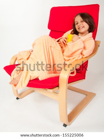 Little girl, caucasian, european, brown hair, blue eyes, sitting cozy in an armchair and drinking tea, having a flu