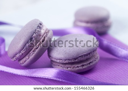 Violet French macaroons cookies stack on violet fabric, with violet ribbon