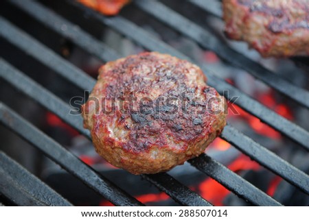 Hamburger patty on a charcoal grill