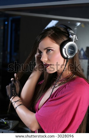 Attractive girl DJ in sound room with headphones.