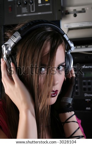 Attractive girl DJ in sound room with headphones.