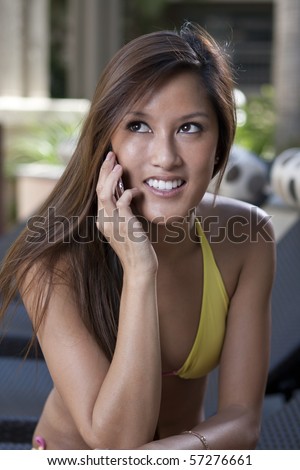 stock photo cute asian girl with a smart phone in a yellow bikini