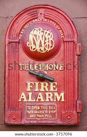 Fire alarm box with handle to turn and open to set off alarm labeled \'in case of emergency\' from the front of an 1800s fire station