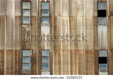 Windows on a rusty corrugated iron wall at a disused power station.