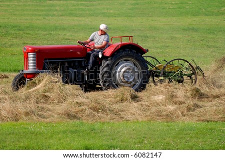 European Union farmer on the old red tractor is working with hay