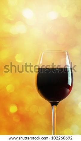 glass with red wine on a yellow background.
