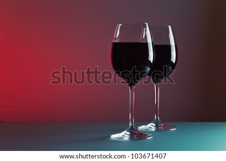 glasses with red wine against of color background.