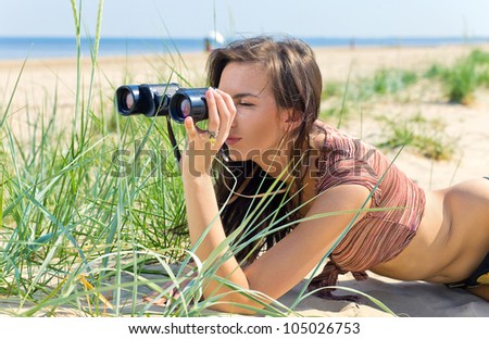young sexy woman with field-glass on a beach.