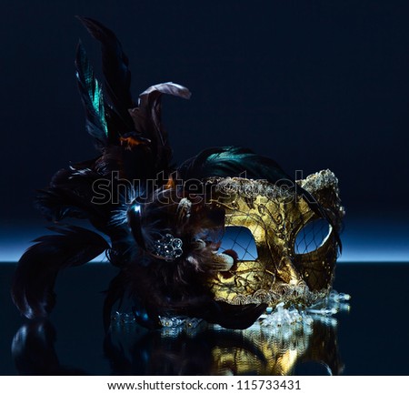 The Venetian mask with feather on a mirror table