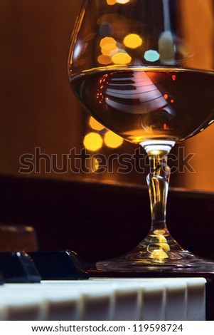 Gratitude for the maestro, snifter with brandy on a piano.