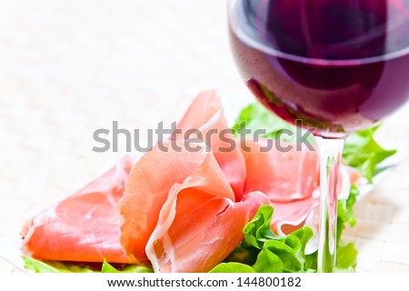glass with red wine and ham with salad