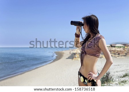 woman in  bikini  with field-glass on a beach