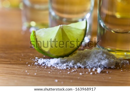 tequila , lime and salt on wooden table