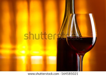 bottle and glass with red wine on  yellow background