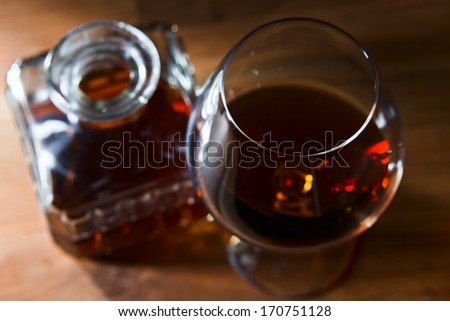snifter with brandy on old oak table, focus on foreground