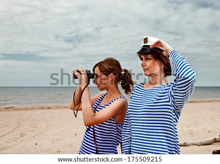 Two girls with field-glass on a beach.