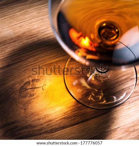 snifter with brandy on old oak table, focus on table