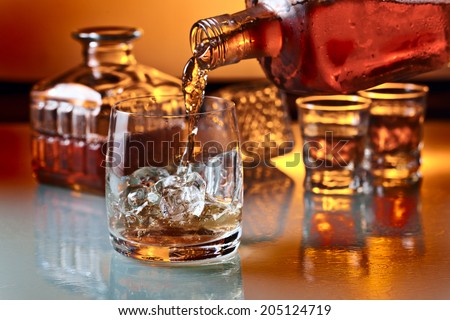 glass with whiskey and ice on a glass table