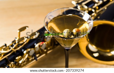 saxophone and martini with green olives on wooden table