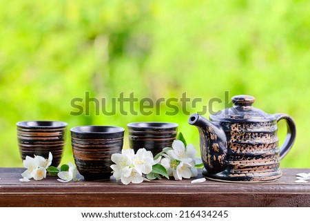 Teapot with small cups and jasmine flowers
