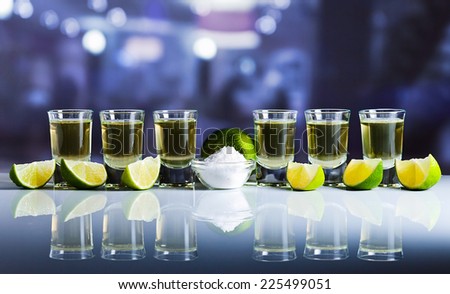 tequila , lime and salt on white reflexive table in bar